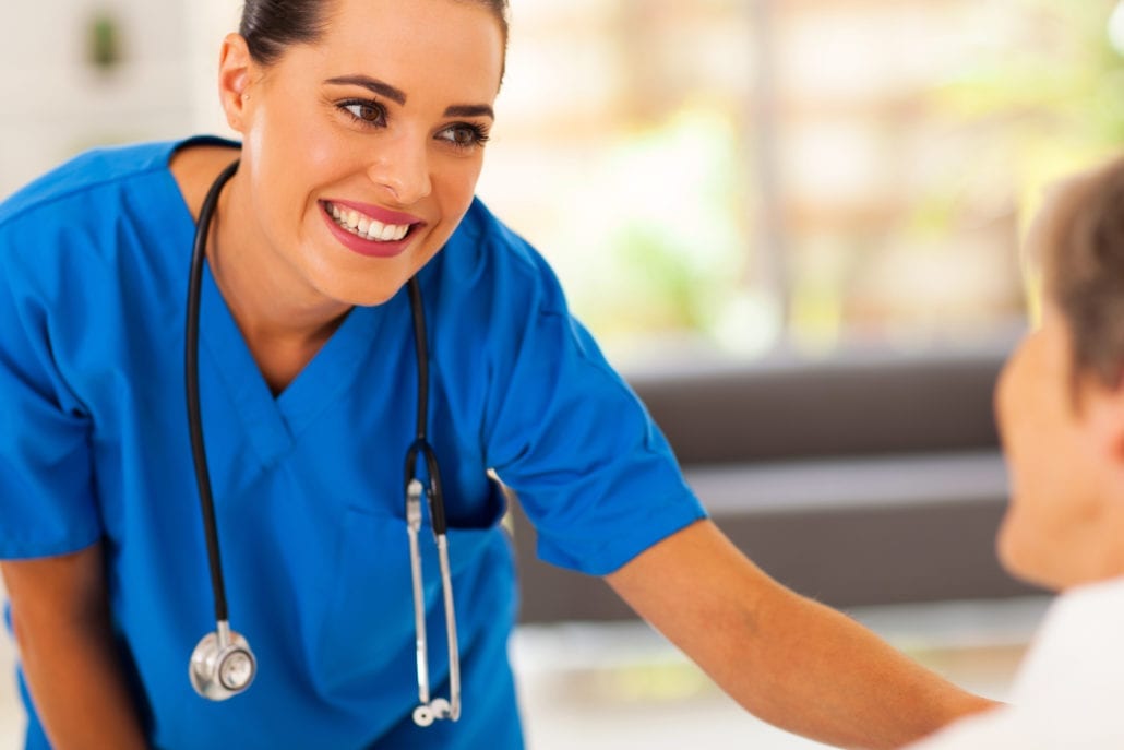 Smiling Nurse reassures patient, blue scrubs and stethoscope