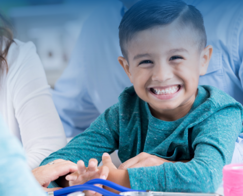United Way health services, young boy smiling at the camera, child sitting at a doctors office with his parents, nurse speaking with child's parents