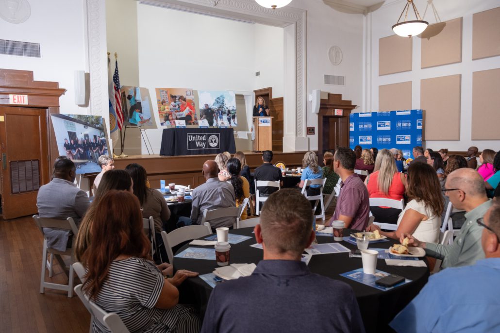 photo of room with guests at tables, and Christina Criser Jackson at podium.